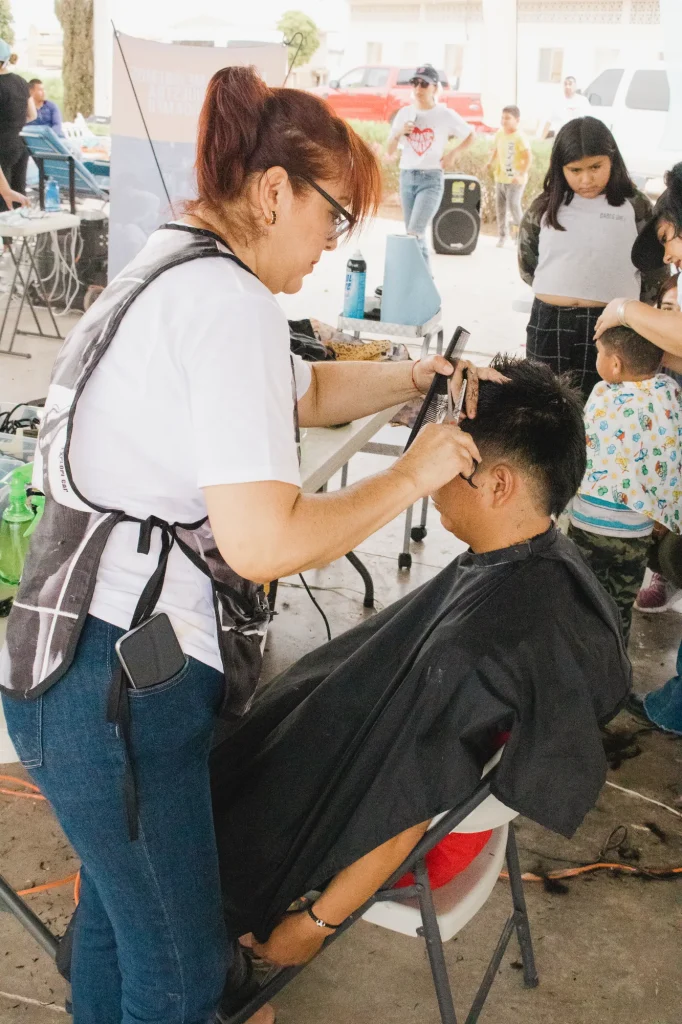 Voluntaria cortando el cabello a un joven en jornada de servicio